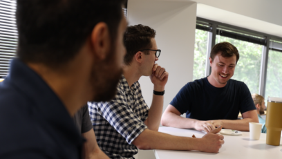 Group of young professionals having a meeting around a table near a window.