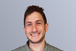 "Smiling man in a green shirt against a light gray background"