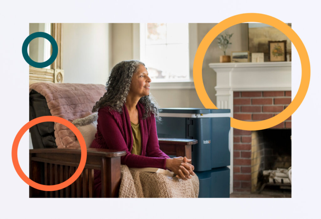 Woman sitting on a wooden chair with a blue recycling bin near a fireplace, colorful circles are overlaid on the image