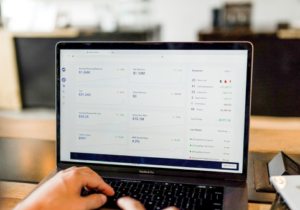 Person using laptop displaying analytics dashboard with financial data and charts.