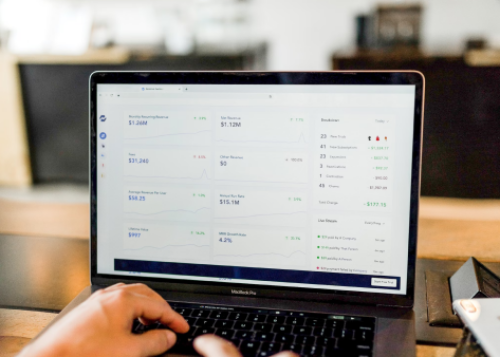 Person using laptop displaying analytics dashboard with financial data and charts.