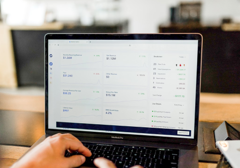 Person using laptop displaying analytics dashboard with financial data and charts.