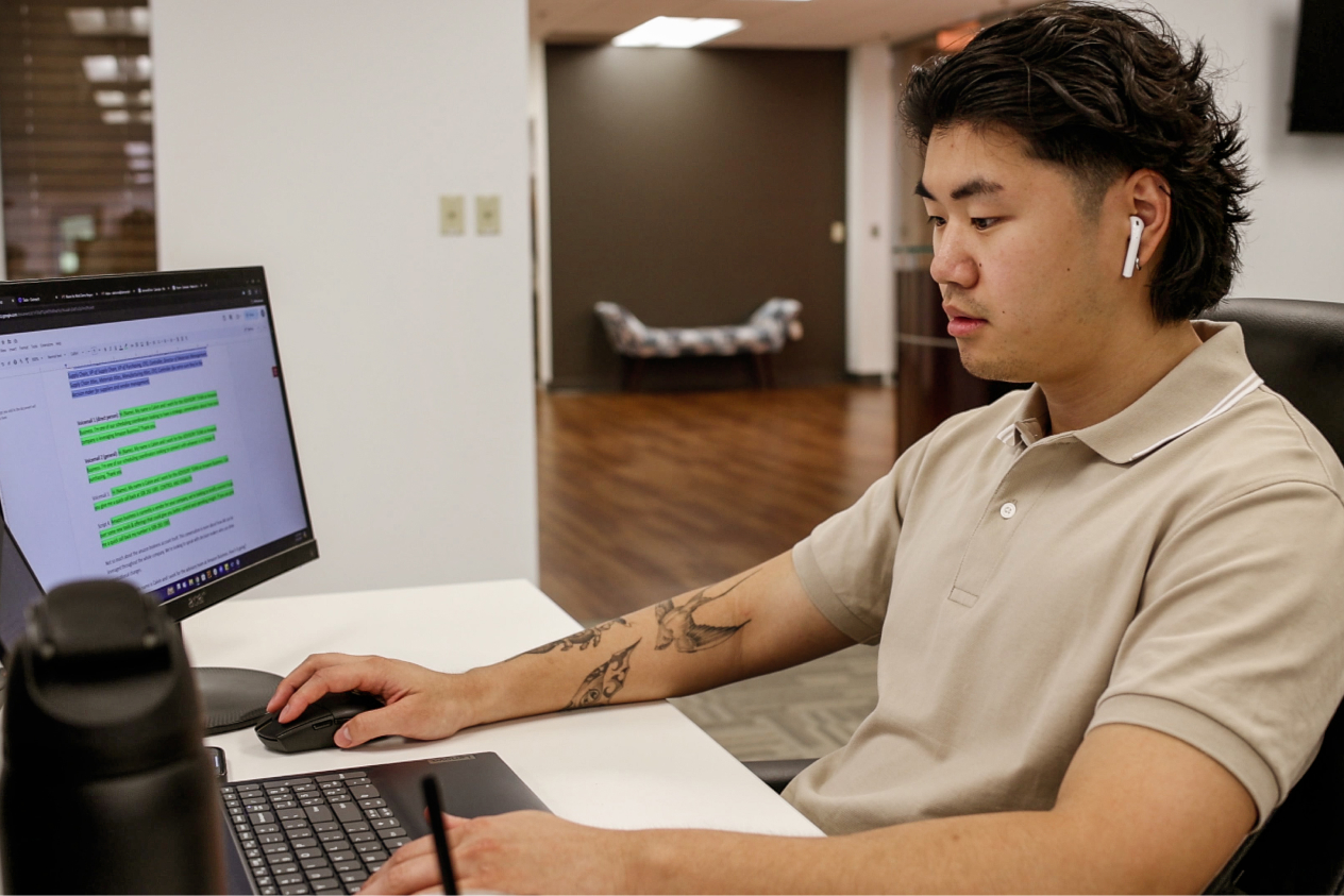Person wearing AirPods and working on a computer at a desk in an office setting