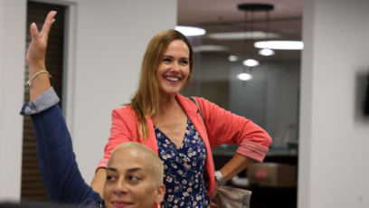 Two women smiling and engaging in a lively discussion in a modern office environment.