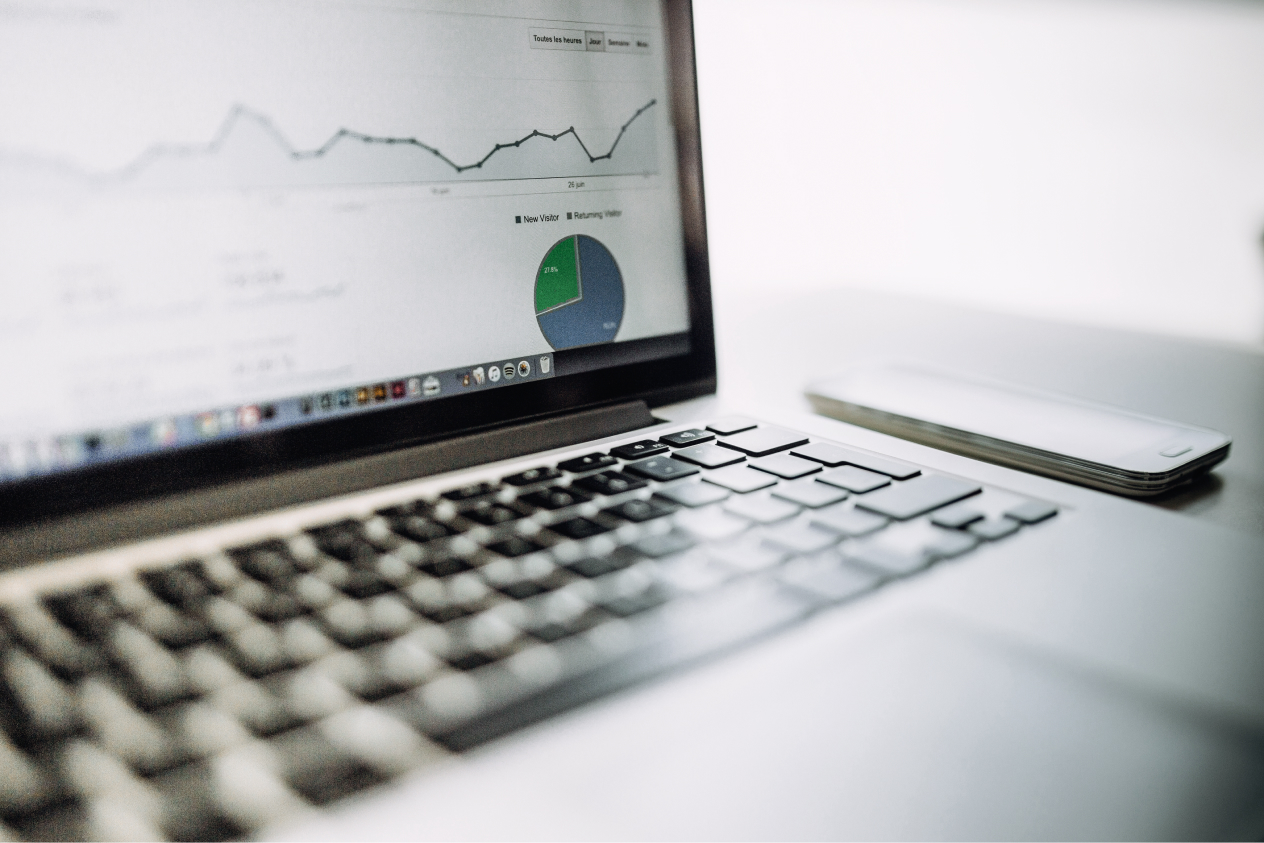 Laptop displaying analytics graph and pie chart with a smartphone placed next to it on a desk