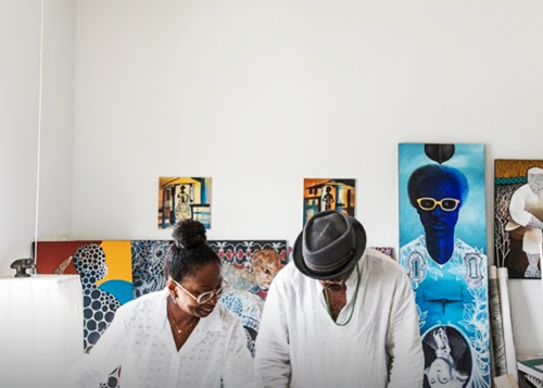 Artists collaborating on a project in a modern studio with paintings and art supplies in the background