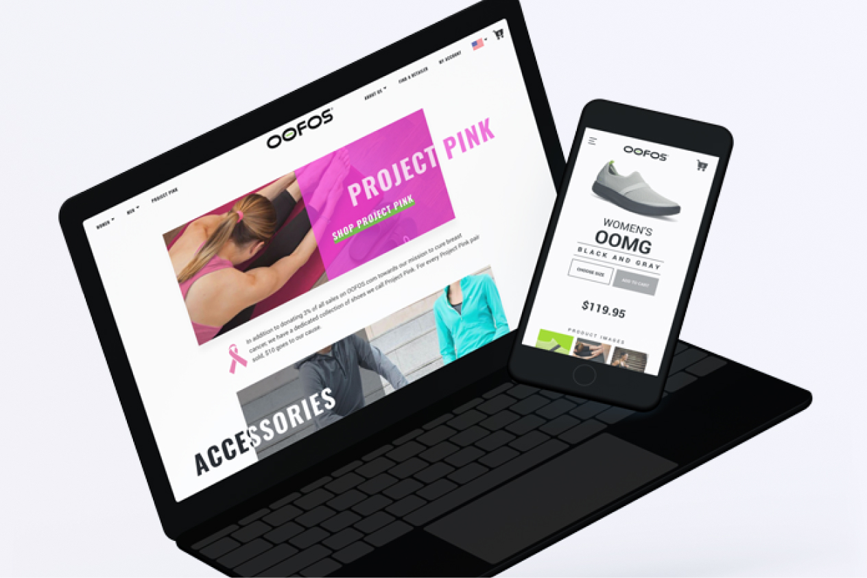 Laptop and smartphone displaying a webpage for OOFOS footwear, featuring Project Pink and women's OOmg shoe in black and gray.
