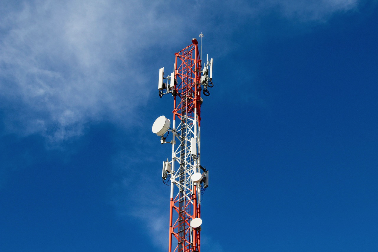 Cellular tower with multiple antennas and communication devices against a clear blue sky